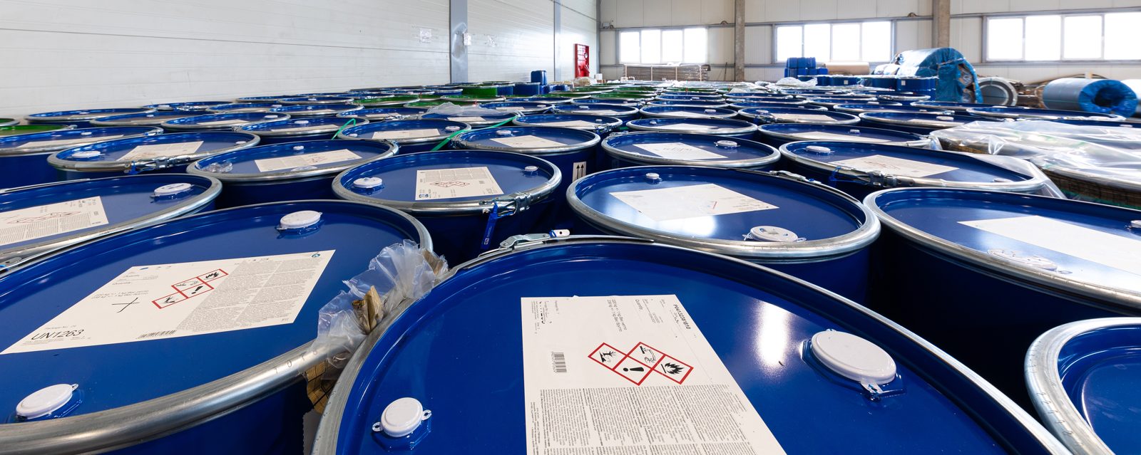 Rows of blue chemical drums in a warehouse, representing products and surplus stock listed on CASINDI